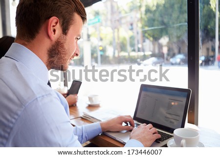 Businessman Using Laptop In Coffee Shop