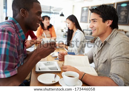 Two Male Friends Meeting In Busy Coffee Shop