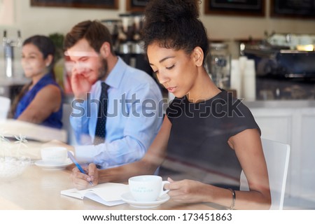 Businesswoman Writing Notes In Coffee Shop