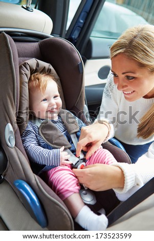 Mother Putting Baby Into Car Seat Mother Putting Baby Into Car Seat