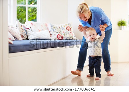Mother Helping Young Son As He Learns To Walk