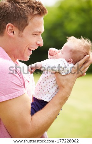 Proud Father Holding Baby Daughter In Garden