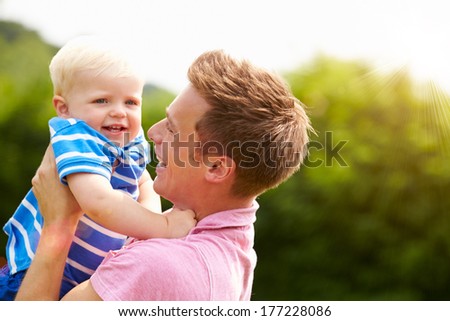Father Hugging Young Son In Garden