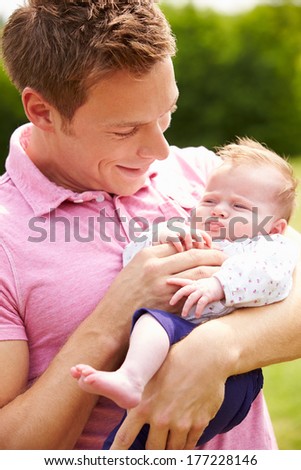 Proud Father Holding Baby Daughter In Garden