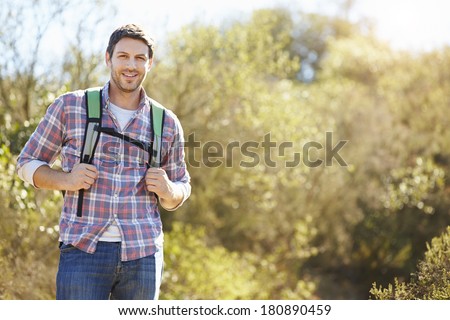 Portrait Of Man Hiking In Countryside Wearing Backpack