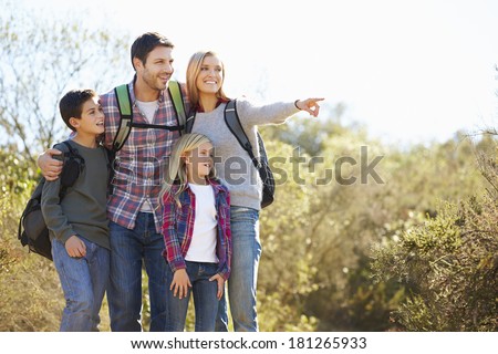 Family Hiking In Countryside Wearing Backpacks
