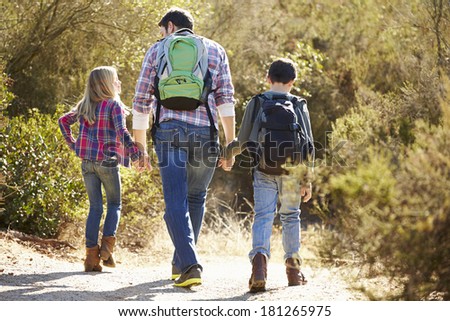 Rear View Of Father And Children Hiking In Countryside