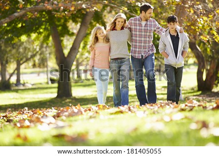 Family Walking Through Autumn Woodland Family Walking Through Autumn Woodland