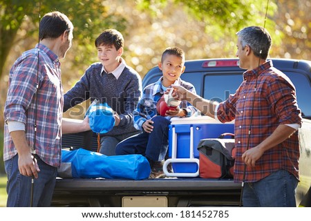 Fathers With Sons Unpacking Truck On Camping Holiday