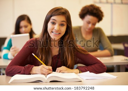 Female High School Student Studying At Desk In Classroom