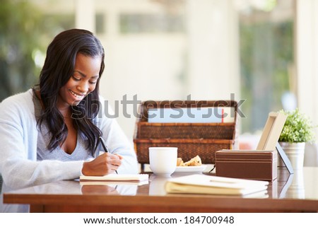 Woman Writing In Notebook Sitting At Desk