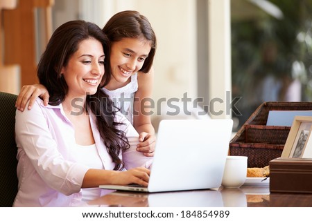 Mother And Teenage Daughter Looking At Laptop Together