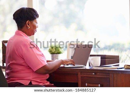 Mature Woman Using Laptop On Desk At Home