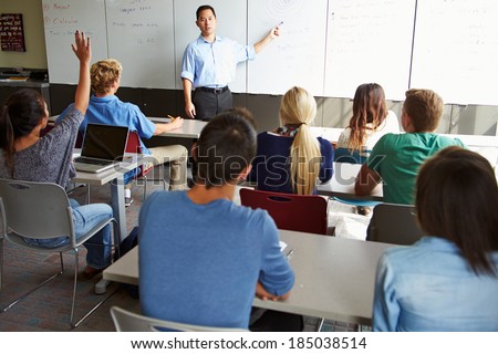 Tutor With High School Students In Class Using Laptops