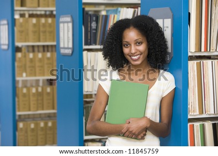 University student holding book in library