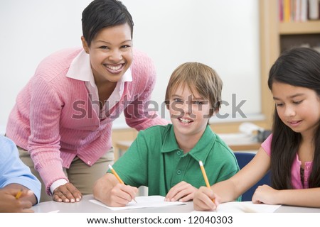 Teacher and pupil in elementary school classroom working on written project