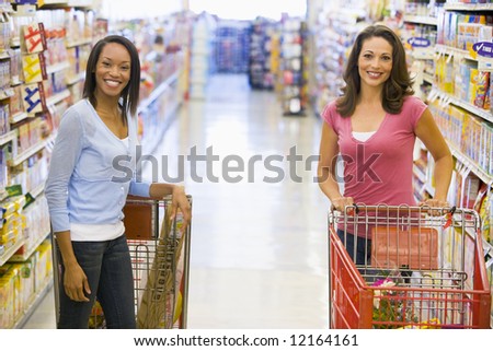 Two woman meeting in supermarket grocery ailse