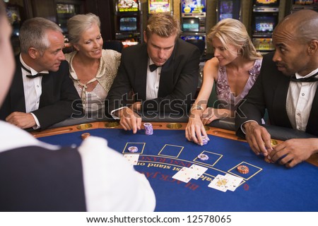 Five people sitting around blackjack table in casino