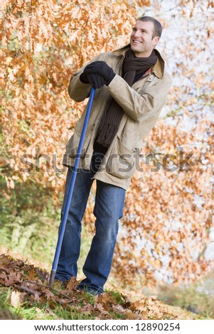 Man tidying autumn leaves in garden