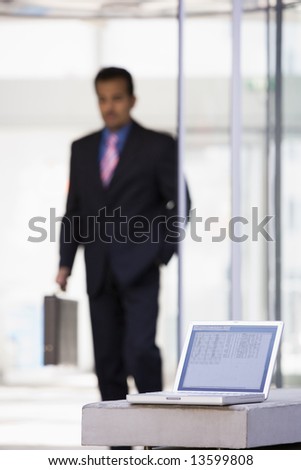 Laptop computer outside office with businessman in background