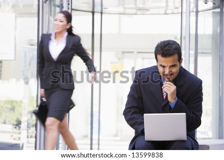 Businessman working outside at laptop outside office