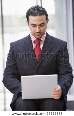 Businessman using laptop outside office