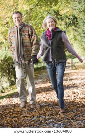 Senior couple walking along path in autumn woods