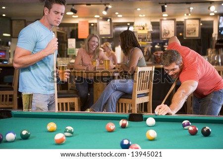 Two young men playing pool at a bar