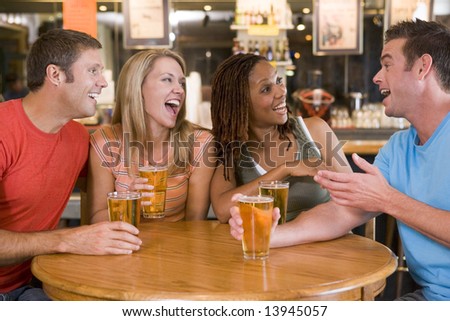 Group of young friends drinking and laughing in a bar