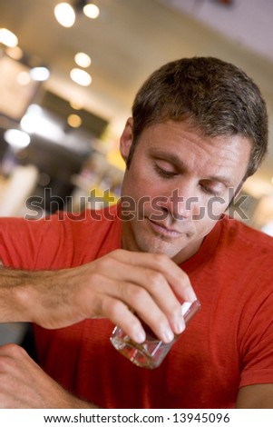 Young man at bar staring forlornly into drink