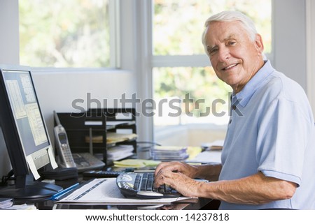 Man in home office using computer smiling