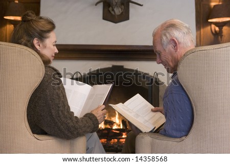 Couple sitting in living room by fireplace reading
