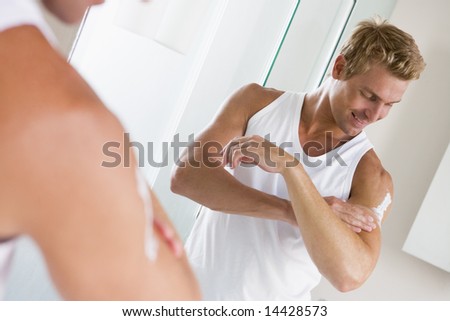 Man in bathroom applying lotion and smiling