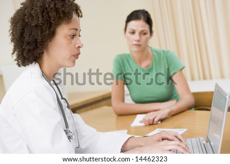 Doctor using laptop with woman in doctor's office frowning