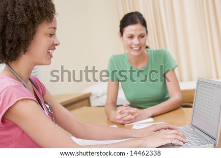 Doctor with laptop and woman in doctor\'s office smiling
