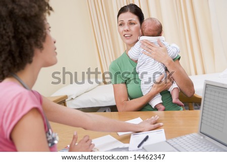 Doctor with laptop and woman in doctor\'s office holding baby