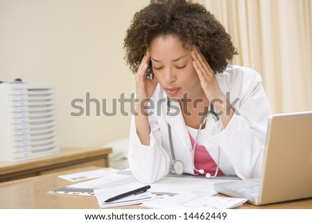 Doctor with laptop and headache in doctor\'s office