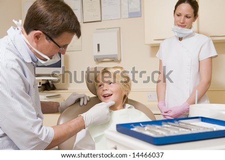 Dentist and assistant in exam room with young boy in chair