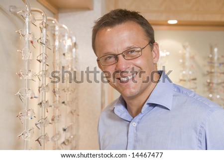 Man trying on eyeglasses at optometrists smiling