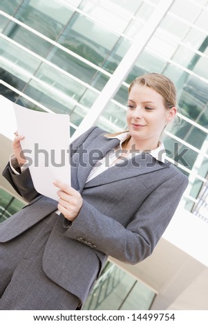 Businesswoman standing outdoors reading paperwork