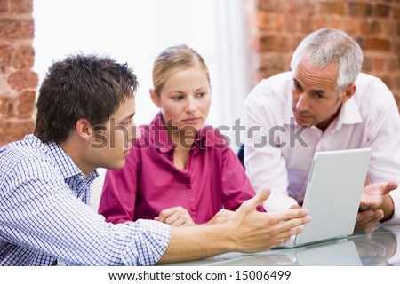 Three businesspeople in office with laptop