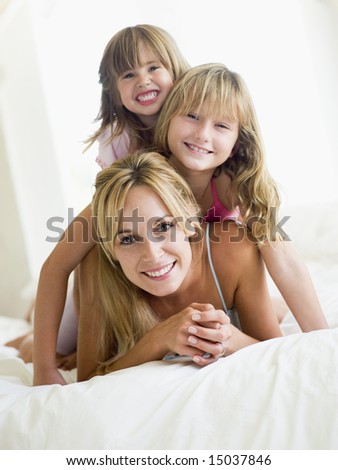 stock photo Woman and two young girls in bed playing and smiling