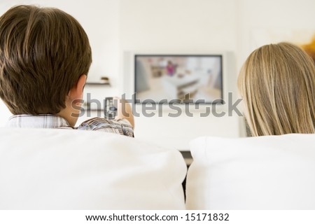 Young boy and young girl in living room with remote control and flat screen television