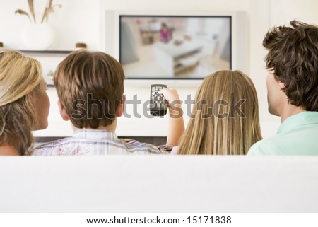 Family in living room with remote control and flat screen television Family in living room with remote control and flat screen television
