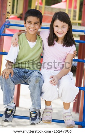 Two children in playground sitting on climbing frame