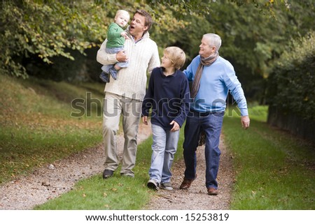 Grandfather walking with son and grandchildren along woodland path