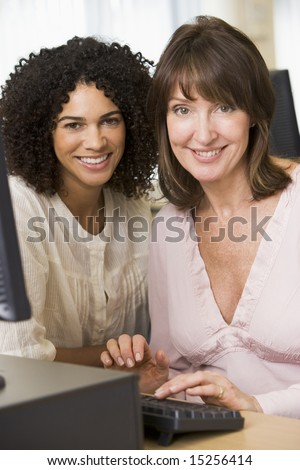 Two female adult students working on a computer together