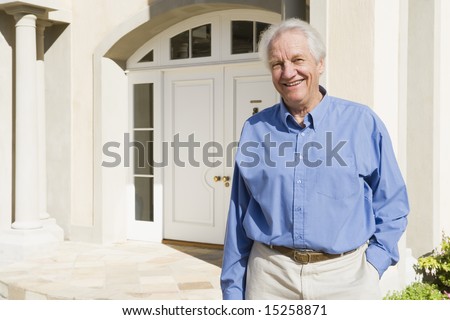 Senior man standing outside front door of house