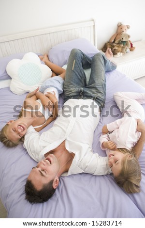 Man lying in bed with two young girls smiling