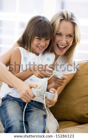 Woman and young girl in living room with video game controllers smiling